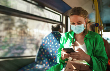 Woman in medical mask with mobile phone in the bus.