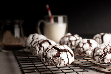 Deliciouse Homemade Chocolate crinkle cookies with powdered sugar icing grate for cooling on dark stone table background. 