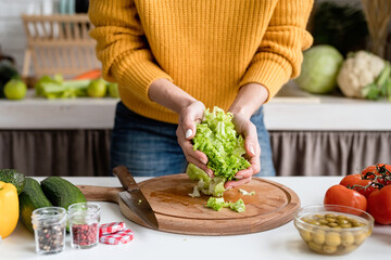 woman preparing greek salad in kitchen cutting lettuce