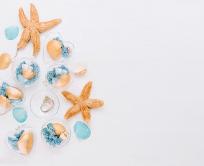 Beach DIY ornaments filled with seashell and moss on white wooden background