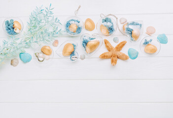 Beach DIY ornaments with seashell and moss on white wooden background