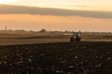 Fototapeta premium Tractor on the field during sunset.