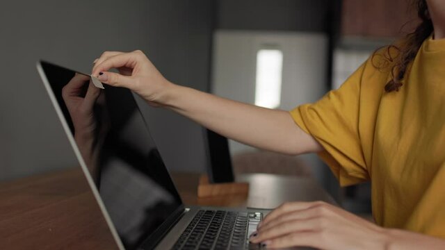 A girl puts a sticker on a camera on a laptop