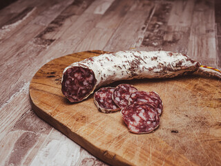 Saucisson sec Pur Porc des Cévennes - traditional French dry sausage, slices of sausage lie on a wooden session, white crust