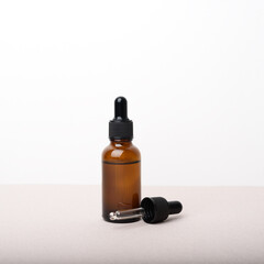 A glass dropper bottle with a pippette with black rubber tip on the beige background. Nature Skin concept. Organic Spa Cosmetics. Close up.