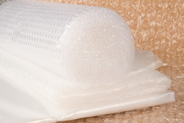 Different types of plastic packaging materials - foamed polyethylen sheets, small and large bubblewrap rolls, PE packaging film on brown paper background. Selective focus