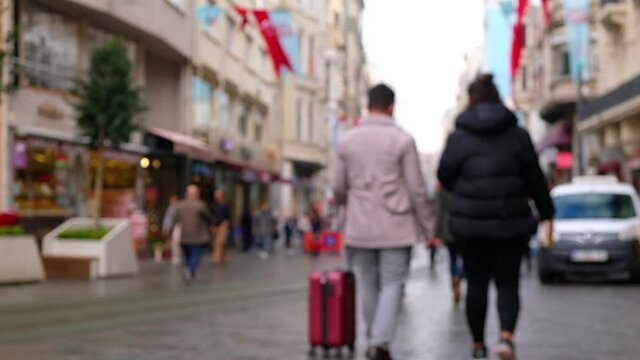 Unrecognizable tourists walk down the street paved pedestrian street in the morning. People at Istiklal Caddesi, Istanbul, Turkey. Defocused video footage