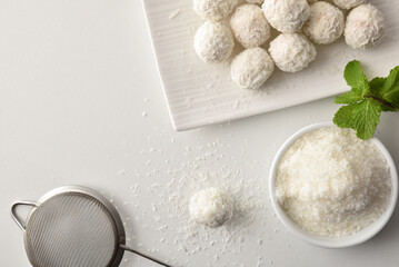 Elaborating coconut balls on white table top view
