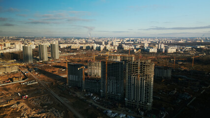 Fototapeta premium Construction site. Construction of modern multi-storey buildings. The work of construction cranes is visible. Against the background of the blue sky. Aerial photography.