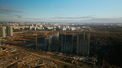 Fototapeta premium Construction site. Construction of modern multi-storey buildings. The work of construction cranes is visible. Against the background of the blue sky. Aerial photography.