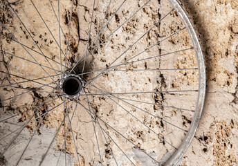 The rim of a bicycle wheel hangs against a brick wall background. Bicycle parts