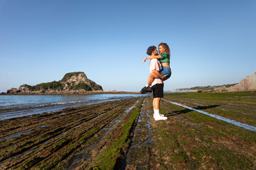 Lovely heterosexual couple on a rocky beach embracing and kissing at the Basque Country.