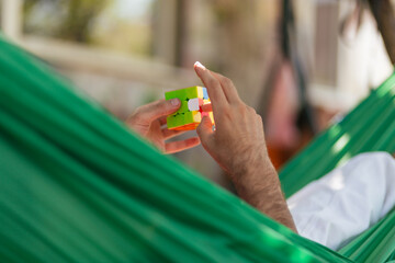 a man resting in a hammock adds a rubik's cube