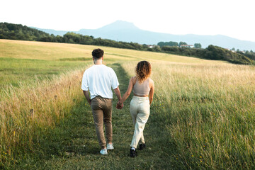 Fototapeta na wymiar Lovely heterosexual couple in a grass field walking and kissing