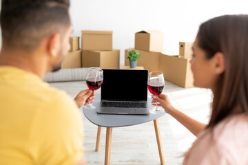Young diverse couple having housewarming party, celebrating with wine, communicating to friends...