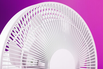 Electric fan in white with a modern design for cooling the room on a pink background.