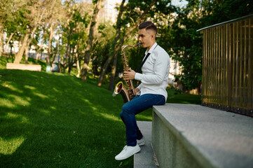 Young saxophonist plays the saxophone in park