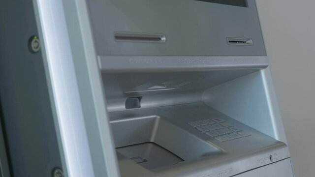 Male hand attaching the card to the ATM machine, withdrawing money from account. HDR. Automatic machine for cash withdrawal.