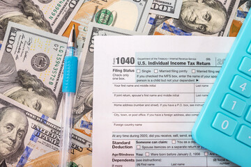 tax forms 1040, blue calculator and pen