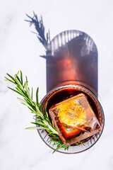 alcoholic cocktail negroni with a block of ice on a light background with a shadow