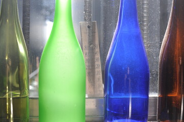 Empty glass bottles standing in a row, green, blue and brown