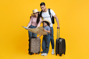 Happy Young Family With Little Daughter Looking At Map, Planning Travel