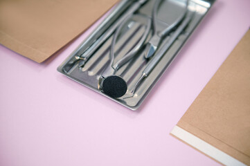 Close-up of a set of sterile stainless steel instruments for professional pedicure on colored...