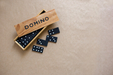 Domino game in wooden box on brown background, top view. Board game