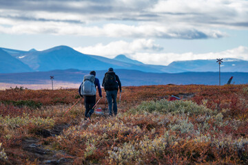 Fototapeta na wymiar Friends Trail running in outdoors or Trekking clothings with Backpacks on high mountain in Pieljekaise national park South of Jakkvik Sweden.