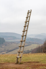 Obraz premium Old wooden ladder on the meadow leading high up in the sky . Ladder to heaven. Symbol of career.
