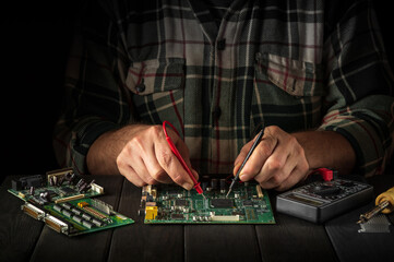 Computer or electronics repair. Master tester checks the electronic board in the workshop.