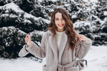 Close up portrait of a girl walking in a snowy park laughing and wearing a coat