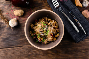 Raw vegan vegetable risotto and microgreens in bowl on rustic wooden background.