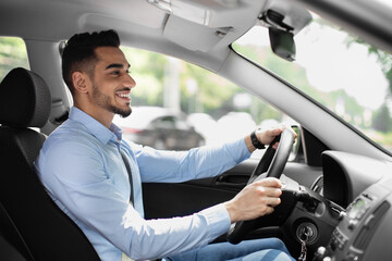Joyful arabic guy driving nice auto, side view - Powered by Adobe
