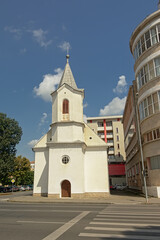 Fototapeta na wymiar Small modest evangelic church in between modern apartment buildings Alba Iulia, Romania