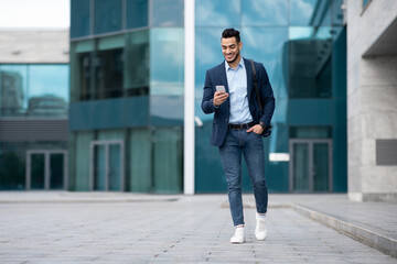 Confident arabic guy programmer with backpack walking by street