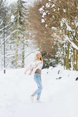 Fototapeta na wymiar Close up portrait of an beautiful girl in a woolen sweater enjoying winter moments. Outdoors photo of a short-haired lady in a pink hat having fun on a snowy morning on a blurred nature background.