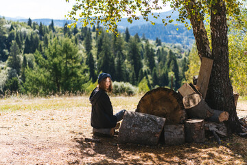 Woman next to logs of cut wood
