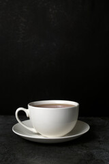 Obraz na płótnie Canvas white cup of tea on a saucer isolated on dark background
