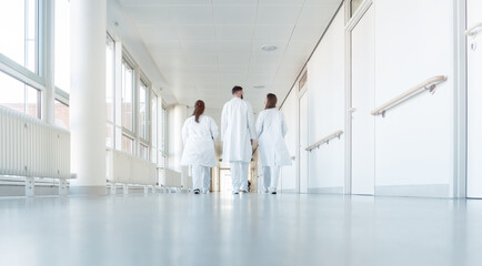 Three doctors walking down a corridor in hospital seen from behind