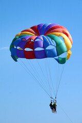 multicolored parachute with two people in the clear sky