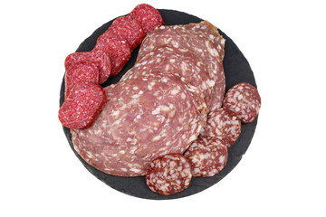 Different tasty sliced salami sausage on a black slate serving board isolated on white background