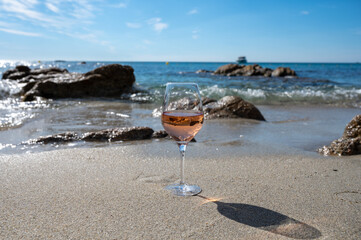 Summer time in Provence, glass of cold rose wine on sandy beach and blue sea near Saint-Tropez, Var department, France