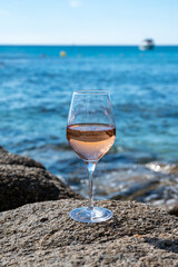 Summer time in Provence, glass of cold rose wine on sandy beach and blue sea near Saint-Tropez, Var department, France