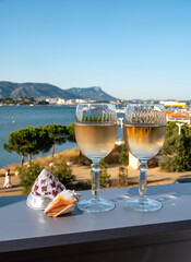 Summer on French Riviera, drinking of cold white or gris rose wine from Cotes de Provence on outdoor terrase with view on harbour of Toulon, Var, France and sea shells