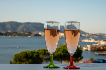 Summer party, drinking of French champagne rose sparkling wine in glasses with view on fishermen harbour of Toulon, France