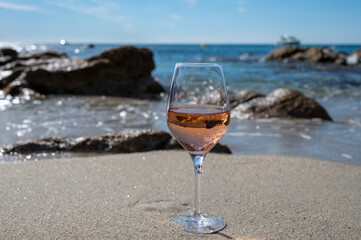 Summer time in Provence, glass of cold rose wine on sandy beach and blue sea near Saint-Tropez, Var department, France