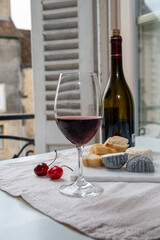 Tasting of burgundy red wine from grand cru pinot noir  vineyards with french goat cheeses and view on old town street in Burgundy wine region, France