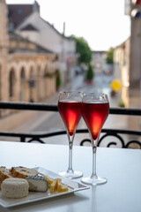 Drinking of Kir Royal,  French aperitif cocktail made  from creme de cassis topped with champagne, typically served in flute glass, with view on old French village