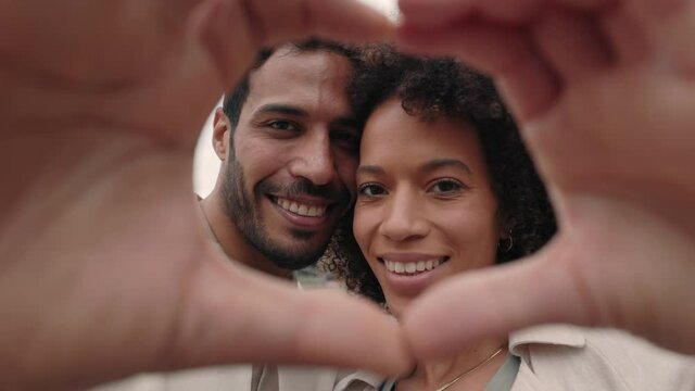 Loving couple making heart with hands and smiling on street